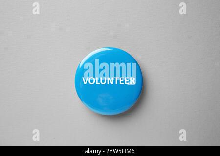 Logo del pulsante con la parola Volunteer su sfondo grigio, vista dall'alto Foto Stock