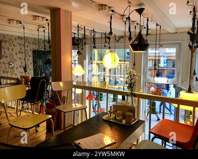 Amsterdam, Paesi Bassi - 8 settembre 2018: Accogliente ed eclettico Cafe Interior con mobili d'epoca, illuminazione creativa e vista sulla strada da una finestra Foto Stock