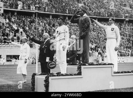 La cerimonia della medaglia dei vincitori del salto lungo. Il podio, la medaglia d'oro Jesse Owens (in piedi al centro), la medaglia d'argento Luz Long (a destra) e la medaglia di bronzo Naoto Tajima (a sinistra). Fotografia d'archivio delle Olimpiadi estive del 1936 a Berlino Foto Stock