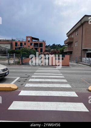 Porto Sant'Elpidio, Italia - 06 luglio 2022: Una tranquilla strada residenziale con un passaggio che conduce a condomini rosa contro un cielo nuvoloso. Foto Stock