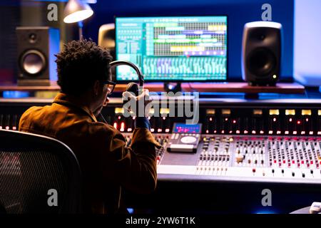 Audio avanzato che regola l'audio su una scheda del pannello di controllo del mixer, concetto di studio musicale professionale. L'esperto tecnico musicale alza il volume e aggiunge effetti su una console di mixaggio, registrando canzoni dal vivo. Foto Stock