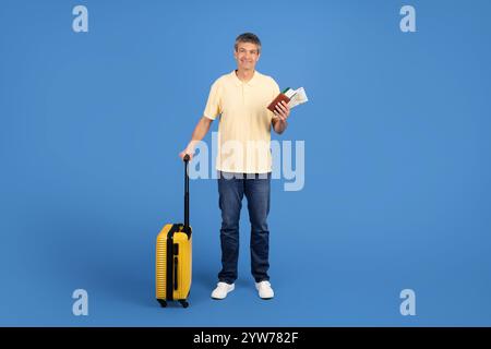 Uomo maturo che si prepara al viaggio con valigia e documenti di viaggio in mano Foto Stock