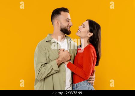 Coppia innamorata che condivide affetto su uno sfondo giallo brillante Foto Stock