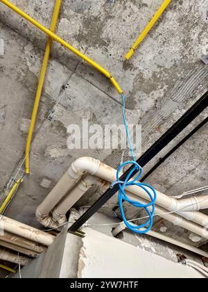 Installazione a soffitto con tubi e conduttori nel cantiere edile Foto Stock