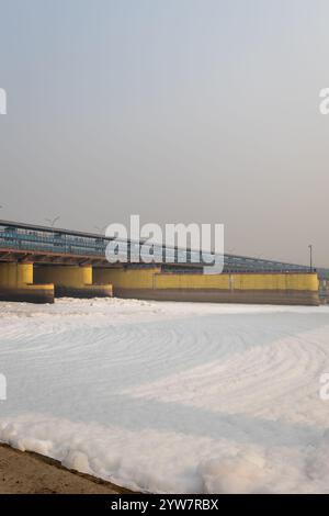 fiume inquinato con effluenti industriali e domestici schiuma tossica e ponte stradale al mattino l'immagine viene scattata presso lo sbarramento del fiume yamuna di okhla delhi india. Foto Stock