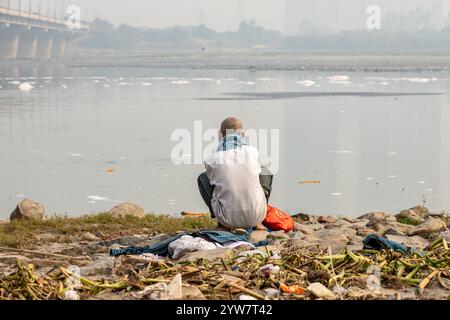 L'uomo isolato che guarda il fiume inquinato con schiuma tossica al mattino viene scattato presso lo sbarramento di okhla del fiume yamuna, delhi, india. Foto Stock