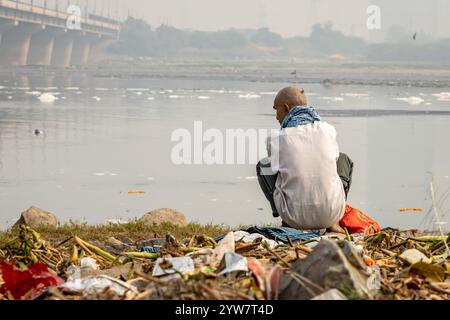 L'uomo isolato che guarda il fiume inquinato con schiuma tossica al mattino viene scattato presso lo sbarramento di okhla del fiume yamuna, delhi, india. Foto Stock