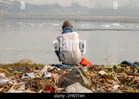 L'uomo isolato che guarda il fiume inquinato con schiuma tossica al mattino viene scattato presso lo sbarramento di okhla del fiume yamuna, delhi, india. Foto Stock