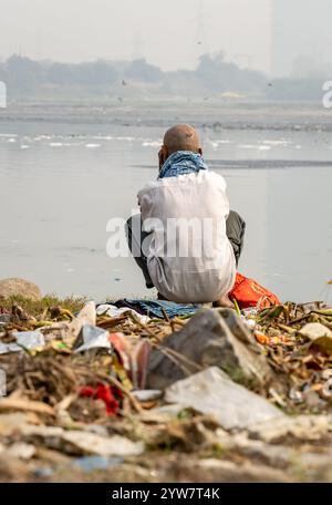 L'uomo isolato che guarda il fiume inquinato con schiuma tossica al mattino viene scattato presso lo sbarramento di okhla del fiume yamuna, delhi, india. Foto Stock