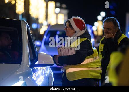 Madrid, Spagna. 9 dicembre 2024. Una donna distribuisce regali durante una nuova edizione di Taxiluz. Circa 200 tassisti volontari stanno portando centinaia di anziani in case di cura e decine di bambini malati in ospedale per le strade del centro di Madrid in una nuova edizione di "Taxiluz". Con questa iniziativa, anziani e bambini hanno potuto godere delle luci natalizie che illuminano Madrid in questo periodo dell'anno. Credito: SOPA Images Limited/Alamy Live News Foto Stock