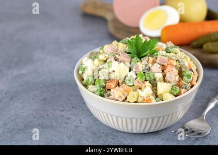 Insalata russa Olivier e verdure per cucinare su sfondo grigio. Tradizionale Capodanno russo e insalata di Natale Foto Stock