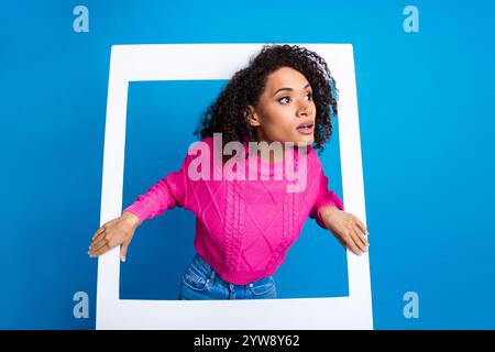 Ritratto fotografico di una bella ragazza con cornice fotografica istantanea, con sbirro della finestra, elegante indumento rosa isolato su sfondo blu Foto Stock