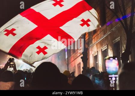 Tbilisi, Georgia - 1 dicembre 2024: Le ragazze stanno con le bandiere UE e georgiane da parte del parlamento. Il raduno su Rustaveli Avenue, lo slogan del raduno è Foto Stock