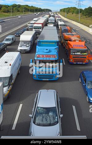 Vista dell'autostrada M25 dall'alto, il traffico stazionario a quattro corsie intrappolato e bloccato alcuni conducenti fuori dai loro veicoli nelle giornate calde e soleggiate dell'Essex, Inghilterra, Regno Unito Foto Stock