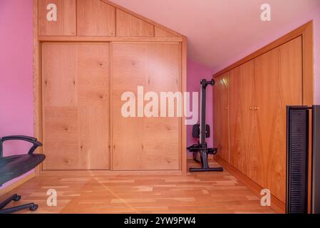 Una camera da letto in un attico con armadi in legno su misura Foto Stock