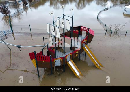 Stourport-on-Severn, Worcestershire, 10 dicembre 2024 - Dennis il dinosauro ha la pancia bagnata. - Il livello dell'acqua è salito attraverso Stourport-on-Severn lunedì, quando la tempesta Darragh ha portato gravi aree di allerta sulle inondazioni lungo il fiume Severn. Un modello di dinosauro in un campo da minigolf, chiamato Dennis dai locali che lo usano come misuratore dell'altezza delle inondazioni, è ora "altezza ventre" Geoffrey la giraffa è anche "profondità del collo" nelle vicinanze. Anche una nave pirata che arrampicava era entrata nelle acque e divenne uno scivolo d'acqua. La zona fieristica di Treasure Island è ora più isola di prima. Crediti: British News and Media/Alamy Live N Foto Stock