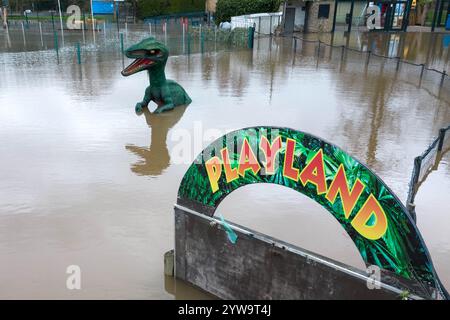 Stourport-on-Severn, Worcestershire, 10 dicembre 2024 - Dennis il dinosauro ha la pancia bagnata. - Il livello dell'acqua è salito attraverso Stourport-on-Severn lunedì, quando la tempesta Darragh ha portato gravi aree di allerta sulle inondazioni lungo il fiume Severn. Un modello di dinosauro in un campo da minigolf, chiamato Dennis dai locali che lo usano come misuratore dell'altezza delle inondazioni, è ora "altezza ventre" Geoffrey la giraffa è anche "profondità del collo" nelle vicinanze. Anche una nave pirata che arrampicava era entrata nelle acque e divenne uno scivolo d'acqua. La zona fieristica di Treasure Island è ora più isola di prima. Crediti: British News and Media/Alamy Live N Foto Stock