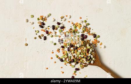 Cucchiaio di legno, con un assortimento di legumi, fagioli, piselli, vista dall'alto, su sfondo chiaro Foto Stock