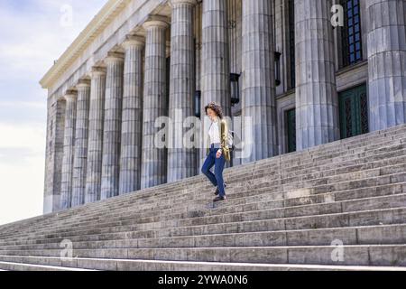 Studente di mezza età che cammina lungo i gradini dell'università Foto Stock