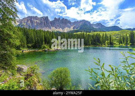 Le acque smeraldo del lago di carezza riflettono la catena montuosa del latemar nelle dolomiti, in italia, in una splendida giornata estiva Foto Stock