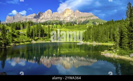 Splendida vista del gruppo montuoso del latemar che si riflette nelle lisce acque color smeraldo del lago di carezza in una soleggiata giornata estiva, sulle dolomiti e sulle alpi italiane Foto Stock