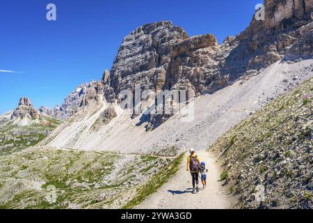 Madre e bambino camminano su un sentiero panoramico nelle dolomiti, godendo della vista mozzafiato delle tre cime di lavaredo in una soleggiata giornata estiva Foto Stock