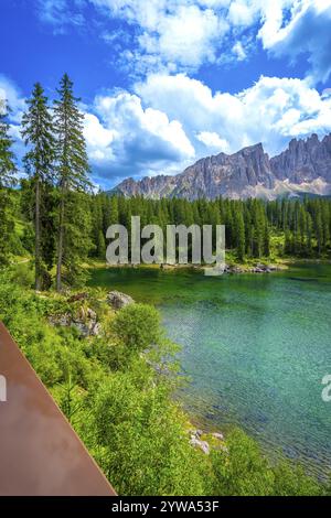 Le acque smeraldo del lago carezza riflettono la catena montuosa del latemar nelle dolomiti in una splendida giornata estiva soleggiata, le alpi italiane Foto Stock