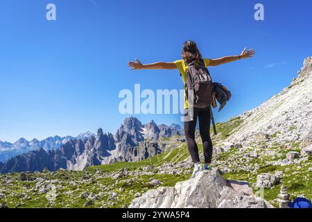 Escursionista a braccia aperte che gode della vista mozzafiato delle tre cime di lavaredo, simbolo delle dolomiti, abbracciando la libertà della natura durante un'escursione Foto Stock