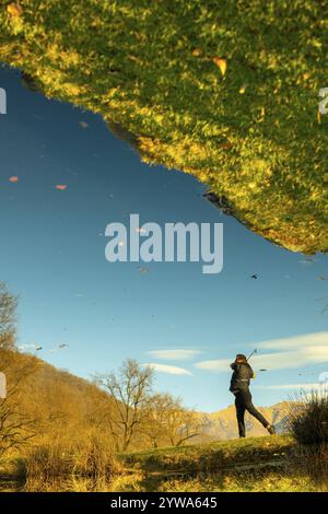 Golfista maschile riflesso in uno stagno d'acqua e colpire il pallone da golf sul Fairway sul campo da golf con la montagna in una giornata di sole in Svizzera. Foto Stock