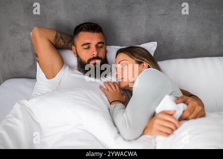 Una giovane coppia sposata sta dormendo nel loro letto. Si stanno abbracciando e si godono un buon sonno. Foto Stock