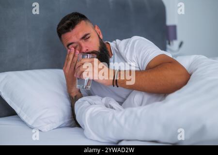 L'uomo si sveglia la mattina e beve acqua. Foto Stock