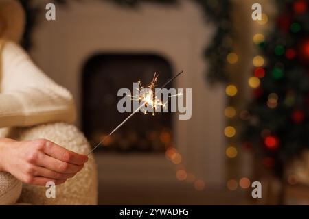 mano femminile che tiene scintillanti sullo sfondo dell'albero di natale da vicino, buon natale. Foto Stock