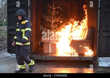 AM Dienstagnachmittag führte die Feuerwehr Hamburg eindrucksvoll vor Augen, wie schnell ein brennender Weihnachtsbaum oder ein Adventsgesteck zur Gefahr werden kann. Dabei Beamte des Trainingszentrums und Lehrgangsteilnehmer ein Wohnzimmer in einen Überseecontainer. Schon kurze Zeit, nach dem Anzünden des Baumes standen bereits Die Coach und der Wohnzimmertisch in Flammen. Dichter schwarzer Brandrauch drang aus dem fiktiven Wohnraum. DAS Löschen mit einem Eimer Wasser oder haushaltsüblichen Kleinlöschern zu diesem Zeitpunkt bereits unmöglich, wie der test simulierte. In der Entstehung des Feue Foto Stock