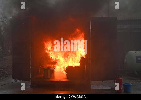 AM Dienstagnachmittag führte die Feuerwehr Hamburg eindrucksvoll vor Augen, wie schnell ein brennender Weihnachtsbaum oder ein Adventsgesteck zur Gefahr werden kann. Dabei Beamte des Trainingszentrums und Lehrgangsteilnehmer ein Wohnzimmer in einen Überseecontainer. Schon kurze Zeit, nach dem Anzünden des Baumes standen bereits Die Coach und der Wohnzimmertisch in Flammen. Dichter schwarzer Brandrauch drang aus dem fiktiven Wohnraum. DAS Löschen mit einem Eimer Wasser oder haushaltsüblichen Kleinlöschern zu diesem Zeitpunkt bereits unmöglich, wie der test simulierte. In der Entstehung des Feue Foto Stock
