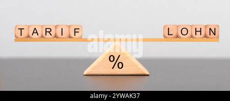 Tarif und Lohn Auf einer Wippe liegen Würfel mit der Aufschrift Tarif und Lohn im Gleichgewicht *** la tariffa e il salario su un alveare sono cubi con l'inscr Foto Stock