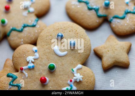 Un piccolo uomo di pan di zenzero decorato di Natale circondato da altri dolci. Cottura natalizia Foto Stock
