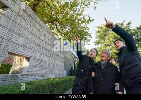 (241210) -- NANJING, 10 dicembre 2024 (Xinhua) -- ai Yiying (2nd R), una sopravvissuta al massacro di Nanchino, cerca i nomi dei suoi parenti, le vittime del massacro di Nanchino, di fronte al "muro del pianto" fuori della sala commemorativa delle vittime del massacro di Nanchino degli invasori giapponesi, a Nanchino, nella provincia di Jiangsu, Cina orientale, 1 dicembre 2024. Per molti anni, è stata una routine annuale per ai Yiying piangere i suoi parenti persi nella sala commemorativa delle vittime nel massacro di Nanchino degli invasori giapponesi. Ai Yiying era una bambina quando la città di Nanchino fu invasa dall'esercito giapponese a Dece Foto Stock