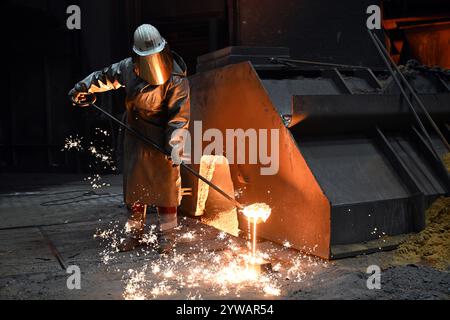 Duisburg, Germania. 10 dicembre 2024. Un dipendente preleva un campione di ghisa fusa in un altoforno. A novembre, ThyssenKrupp Steel ha annunciato che il numero di posti di lavoro nel settore siderurgico sarebbe stato ridotto di 11.000 a 16.000 entro sei anni. Crediti: Federico Gambarini/dpa/Alamy Live News Foto Stock