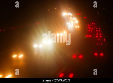 Amburgo, Germania. 10 dicembre 2024. Le luci delle auto nel traffico nelle ore di punta sull'autostrada federale B75 ad Amburgo-Wilhelmsburg brillano attraverso il vetro di una barriera antirumore. Credito: Christian Charisius/dpa/Alamy Live News Foto Stock