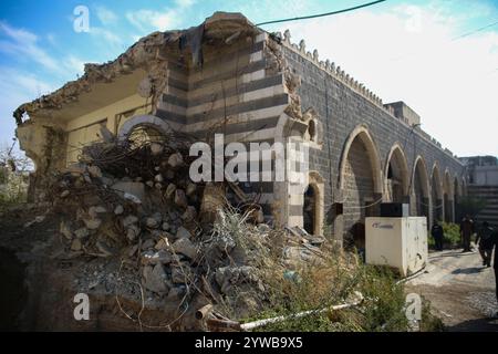 8 dicembre 2024: Homs, Siria. 8 dicembre 2024. Un edificio distrutto attaccato alla moschea Khalid ibn al-Walid di Homs dopo la caduta della città siriana a causa delle forze di opposizione ribelli. Il gruppo islamico di Hayat Tahrir al-Sham, insieme ai gruppi di opposizione siriani alleati, ha dichiarato la cattura di Homs, la terza città più grande della Siria, sabato pomeriggio 7 dicembre. I gruppi ribelli hanno iniziato la loro campagna militare il 27 novembre dal nord della Siria assediando rapidamente territori strategici alle forze governative siriane (Credit Image: © Juma Mohammad/IMAGESLIVE via ZUMA Press Wire) EDITORIA Foto Stock