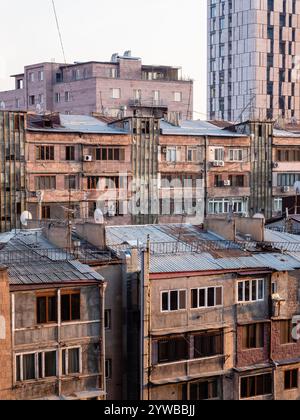 Vista dall'alto delle case di appartamenti piastrellate di tufo nella città di Yerevan al tramonto rosa autunnale Foto Stock