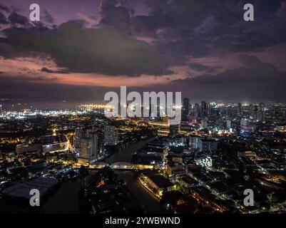 Le luci della città di Manila scintillano al tramonto, formando una vista mozzafiato sotto un cielo spettacolare, che mostra un vivace paesaggio urbano da una prospettiva elevata Foto Stock