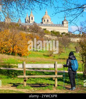 Una donna escursionista di fronte alla facciata sud del monastero reale di San Lorenzo de El Escorial, Madrid, Spagna. Foto Stock