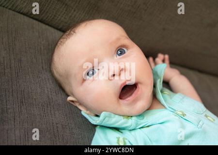 Primo piano di un bambino sdraiato su un divano che sbadiglia Foto Stock