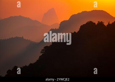 L'aria, carica di particelle e umidità, è attraversata da una luce incredibilmente arancione e rossastra, le sagome delle montagne sembrano fantasia, Foto Stock