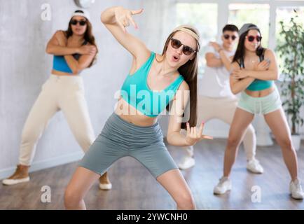 Adolescente che pratica movimenti di danza energici con un gruppo di adolescenti in classe di coreografia Foto Stock