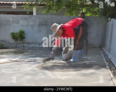 Pattaya, Thailandia 29 novembre 2024, un operaio qualificato applica meticolosamente una finitura decorativa al calcestruzzo appena versato. Foto Stock