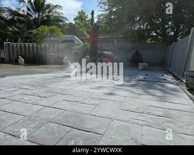 Pattaya, Thailandia, 29 novembre 2024, lavoratori qualificati stanno applicando tecniche di calcestruzzo stampato sotto il cielo luminoso, mostrando arte nell'edilizia. Foto Stock