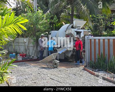 Pattaya, Thailandia, 29 novembre 2024, i lavoratori sono impegnati in un sito residenziale mentre preparano e versano calcestruzzo per una superficie splendidamente stampata. Il sole illumina l'ambiente circostante Foto Stock