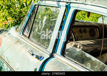Un'auto con interni blu e parabrezza sporco. L'auto è vecchia e ha molta ruggine Foto Stock